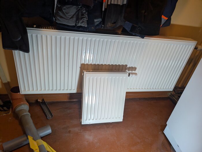 Radiatorer i pannrummet, en större ovanför en mindre på golvet.