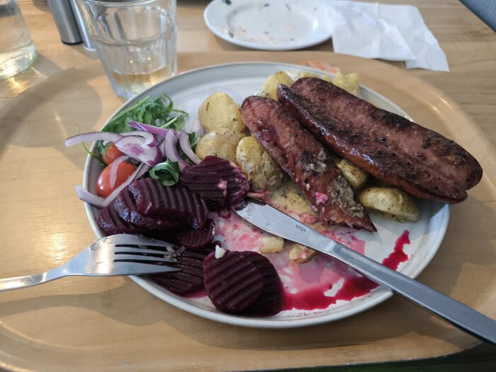 Tallrik med isterband, stuvad potatis, rödbetor, körsbärstomater och rödlök.