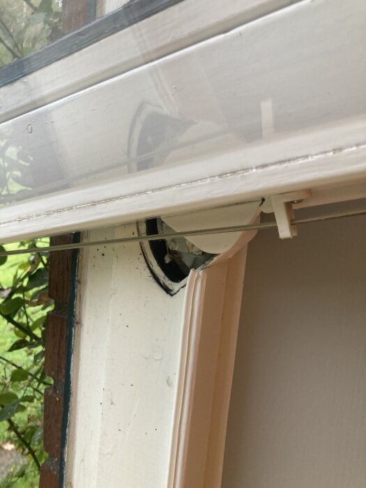 Fönsterbåge med gamla svänggångjärn monterad i ett fönster, fotograferad i närbild.