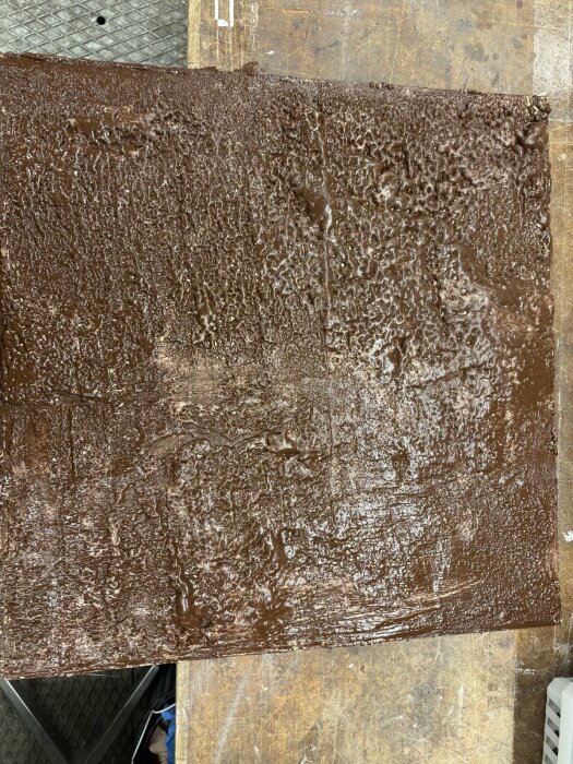 En träskiva med jämnt applicerad brun silikonfärg, används för att testa hållbarheten för limning av kork i bastumiljö.