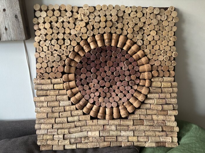 En kvadratisk tavla gjord av vinkorkar arrangerade i cirklar och rader, monterad på väggen som en del av ett korklimningstest för bastu.