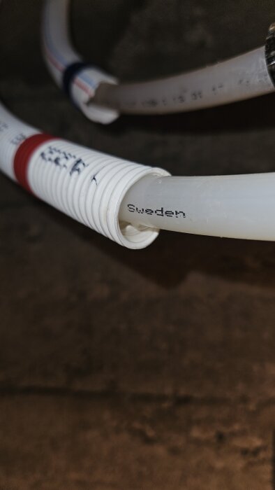 Närbild på ett PEX-rör inuti ett skvallerrör, med vattenansamling längst ut. Text "Sweden" syns på insidan av röret.
