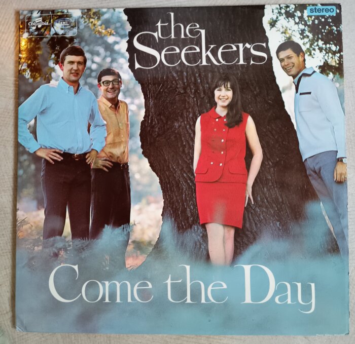 Ett albumomslag för "Come the Day" av The Seekers, en grupp på fyra personer, framför ett stort träd.