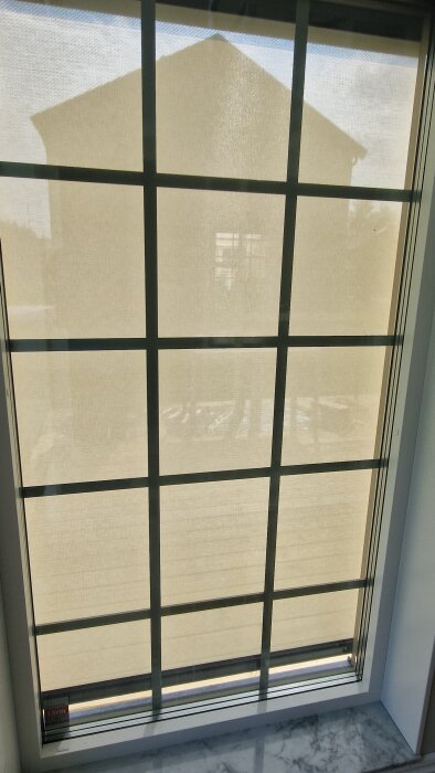 Fönster med glasfiberväv som har 5% genomskinlighet, tillåter ljus att passera och visar en diffus bild av ett hus utanför.