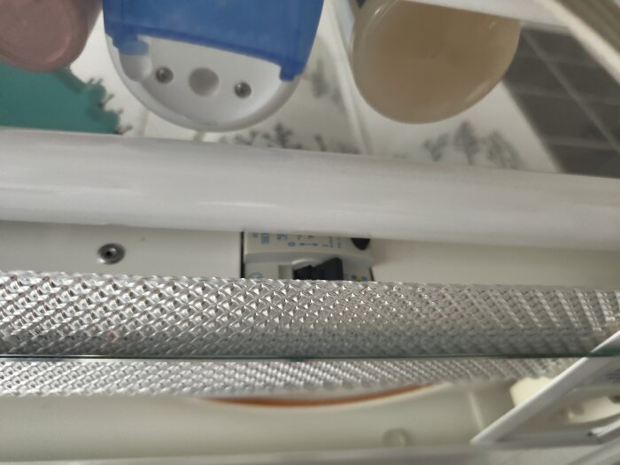 Insida av lysarmatur med synlig switch och lysrör, placerad nära duschutrymme.