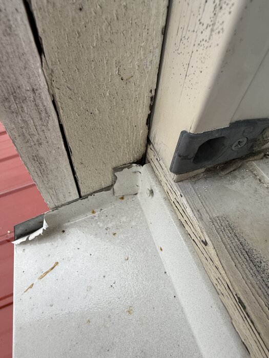 Närbild på fönsterhörn där tätning och lösull har tagits bort för att undersöka vattenläcka vid kraftigt regn.