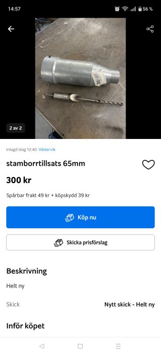 Borrtillsats och borrspets liggande på ett metallbord, visas med en vit etikett på borrtillsatsen.