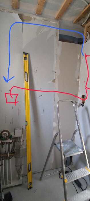 Stege och vattenpass i rum med elinstallation, markerade röda och blå linjer för kabeldragning, elcentral synlig till höger.