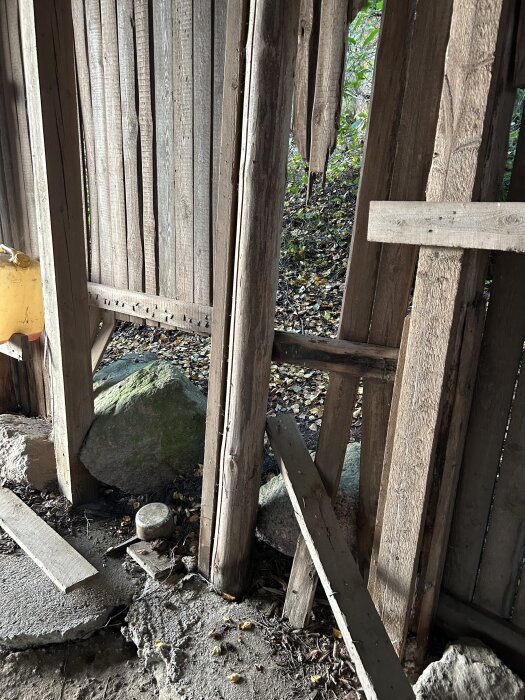 Gammal hölada med ruttna trästockar och brädor. Takstöden har kollapsat och väggarnas brädor är böjda på grund av sättning. Förråd av jordbruksmaskiner.