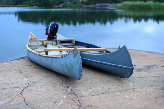 Två sammankopplade kanoter ligger intill vattnet, en med en motor monterad baktill, skapade som en katamanot.