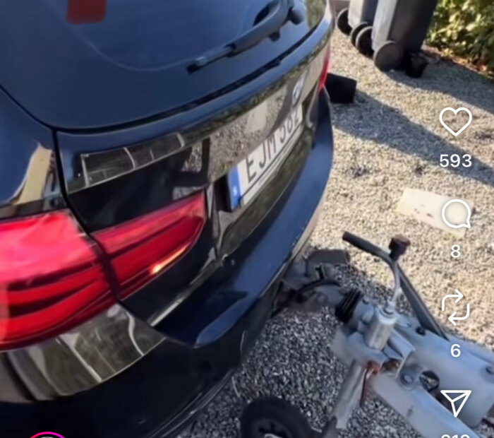 Svart bil bakifrån med dragkrok kopplad till en släpvagn på grusväg.