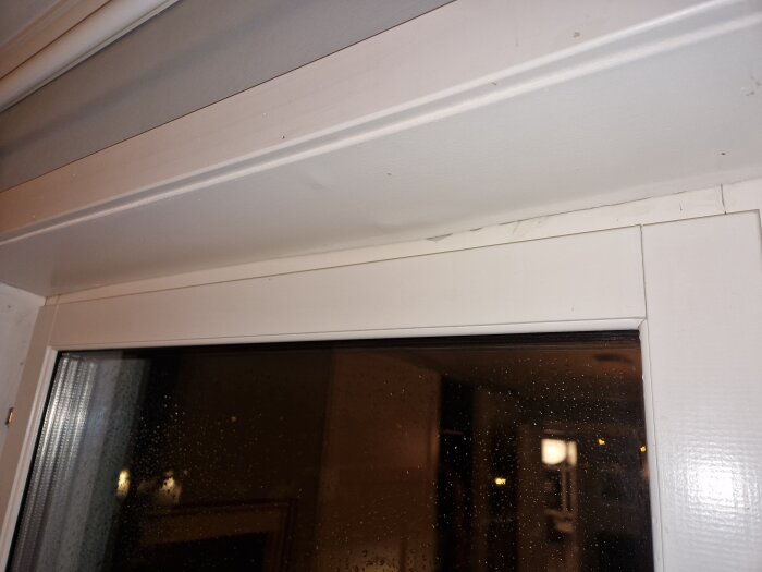 Vattenläckage ovanför balkongdörrens karm på övervåningen, med fuktfläckar synliga.