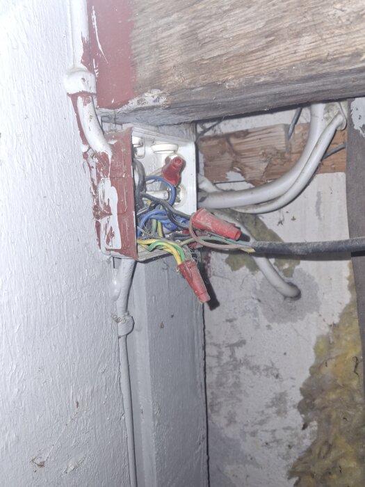 Gammal elcentral i ett hus från 1946 med kablar i olika färger och kopplingsplintar, samt trä- och gipsväggar i bakgrunden.