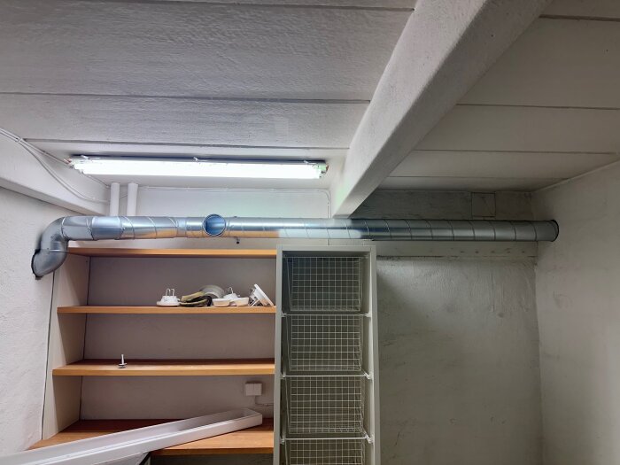 Rördragning i tvättstuga som blockerar det övre hyllplanet, med ett rör som löper horisontellt nära taket ovanför hyllan.