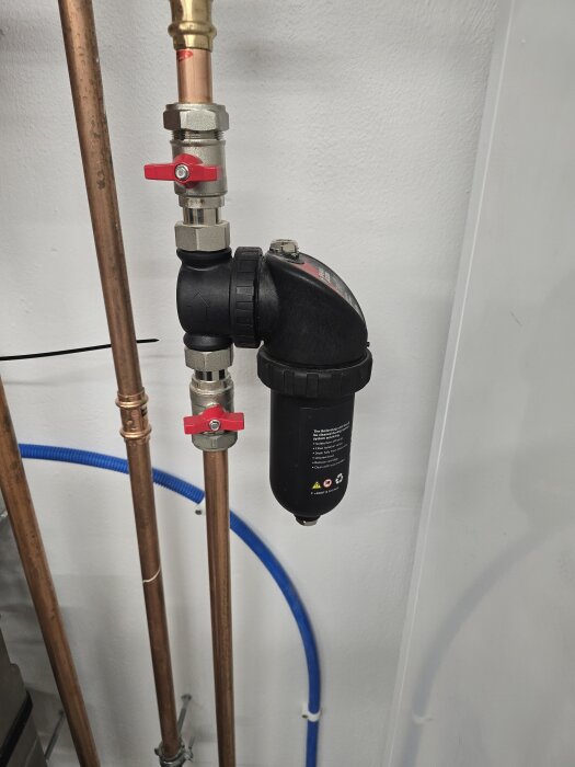 Kopparrör och ett magnetitfilter med avstängningsventiler, installerade i en vägg nära en ny tvättstuga, används för värmesystemet.