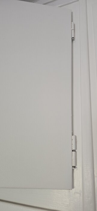 Närbild på en garderobsdörr med gångjärn, visar att dörren inte går att stänga helt på grund av positionen av gångjärnet.