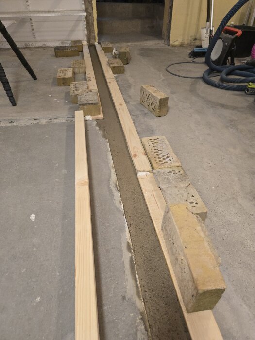 Betonggjutning i träform stödd av tegelstenar under byggprojektet för innervägg.