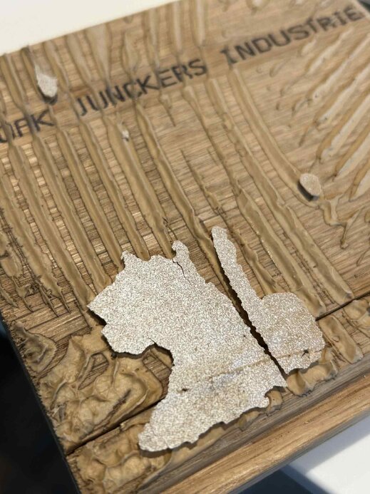 Skadat trägolv där ytskiktet flagnat, visar sprucken och ojämn yta; misslyckad omslipning.