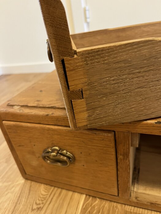 Ett gammalt träarkivskåp med låda där fronten har lossnat, redo för renovering med trälim och tvingar.