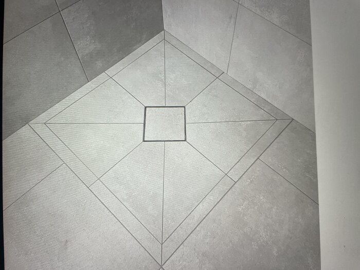 Grå golvplattor i ett mönster med större och mindre kvadrater i mitten.