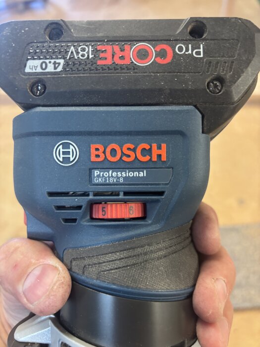 Bosch GKF 18V-8 kantfräs hålls i handen, med synlig hastighetsinställning och etikett för 4.0 Ah batteri.