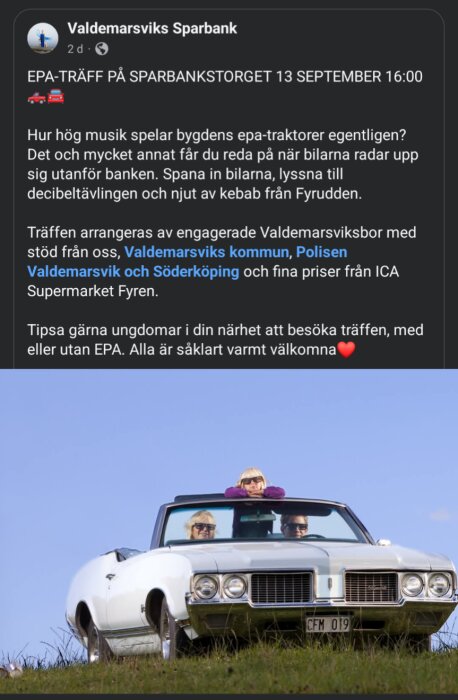 En vit klassisk cabriolet med personer som sitter i bilen och lutar sig fram, stående på en grön äng mot en klarblå himmel.