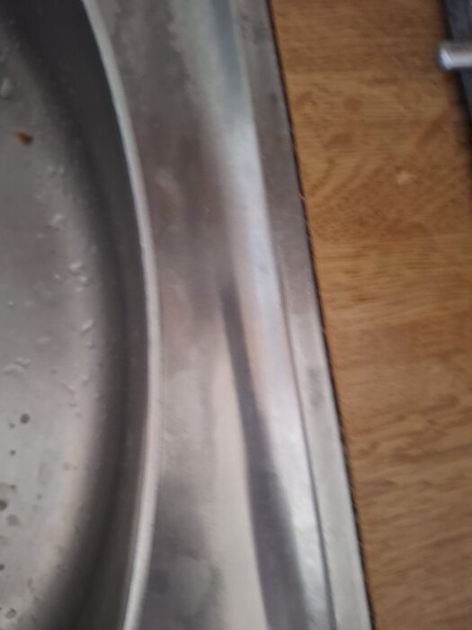 Missfärgad diskbänk i metall bredvid träbänk.