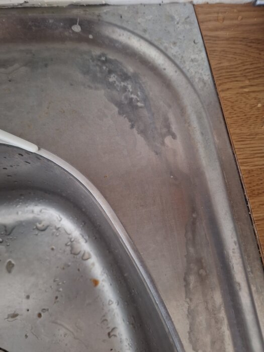 Diskbänk med stora missfärgningar efter rengöring, vattenfläckar synliga.