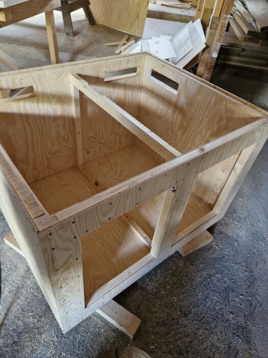 Träkonstruktion av plywood formad som en låda, avsedd för att transportera hundar på flaket av en pickup.