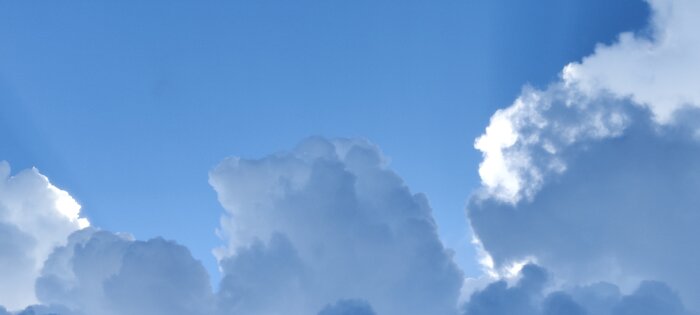 Mörka åskmoln rör sig över en klarblå himmel.