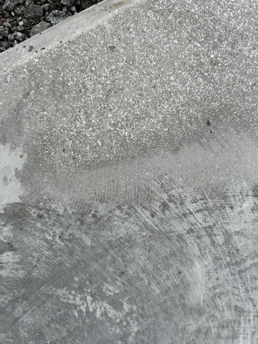 Betongplatta med synlig ballast och slipmärken, samt små håligheter där ballast lossnat, vilket kan leda till smutsansamling.