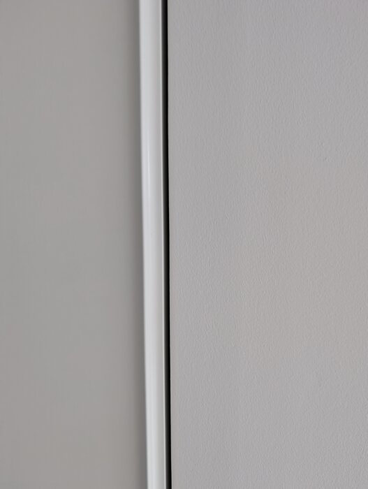 Glapp mellan skjutdörr och innervägg, med hörnskydd på gipsvägg synligt. Dörren ligger dikt an endast vid tak och golv, vilket skapar ojämnhet.