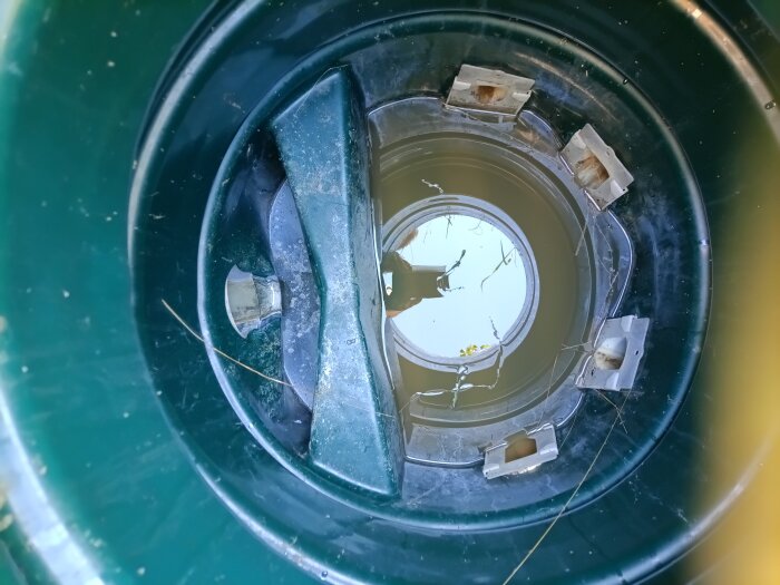 Inuti en fördelningsbrunn med fyra öppningar och vatten i botten, omgiven av grön plast och monteringsfästen.