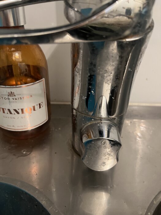 Närbild av en blandare ovanpå en diskbänk med en tvålpump i bakgrunden.