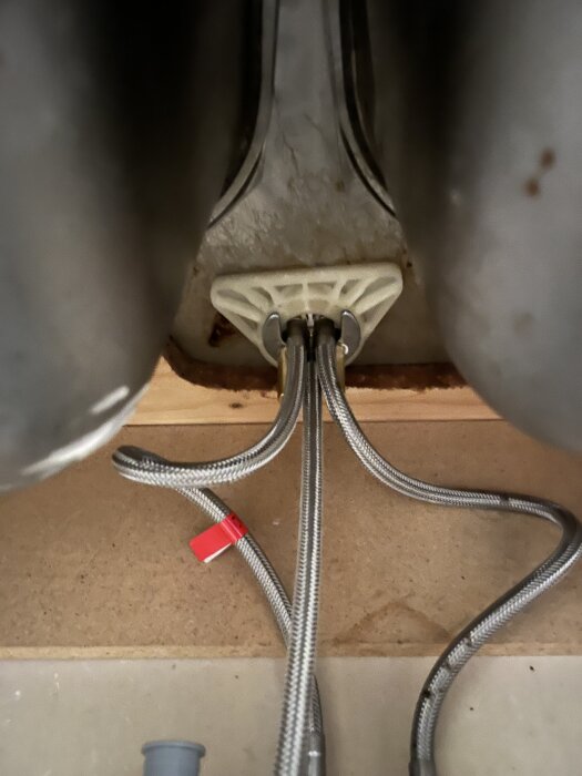 Bild på vattenrör och avlopp under diskhon, med synliga anslutningar och grå slang, i en hyresrätt med begränsat utrymme för diskmaskin.