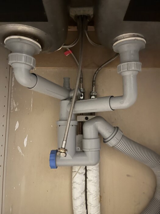 Rör och avlopp under diskho med anslutningar för vatten och avlopp i hyrkök.