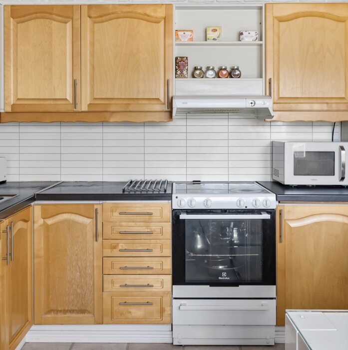 Träkök med spis, mikrovågsugn och köksskåp.