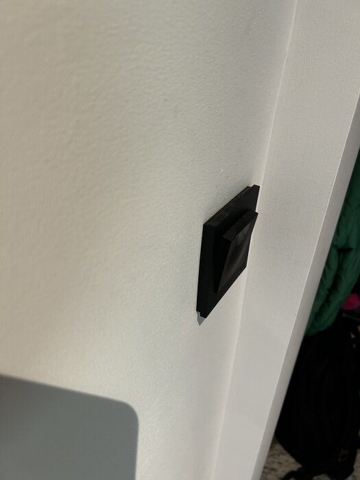 Svart elko plus knappdimmer monterad på en vit vägg.