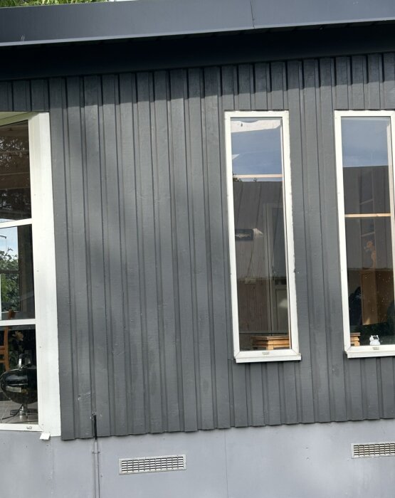 Grått uterum med stående panel av färgen Jotum Aska och en grund av Jotun Shadow, fotograferat i eftermiddagsljus.