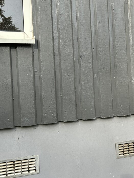 Uterummets panel i färgen Jotum Aska och grunden i Jotun Shadow, med eftermiddagsljus och två ventiler synliga.