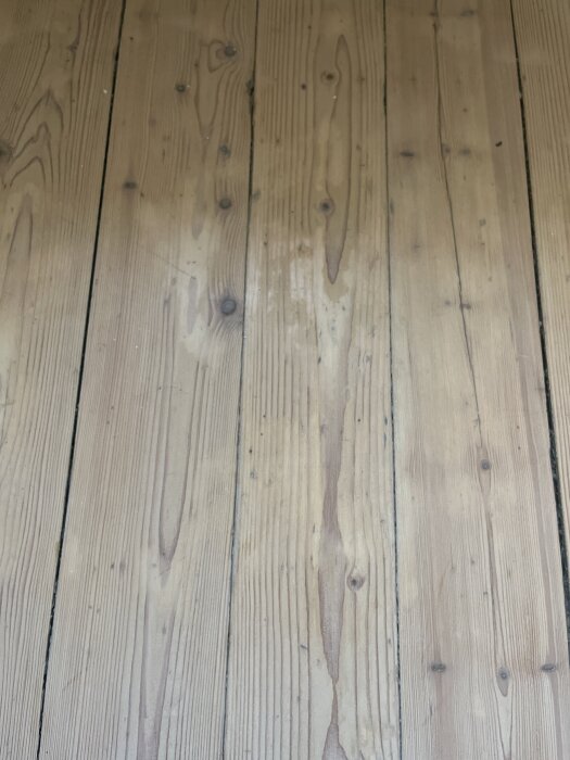 Trägolv med flammig och ojämn yta i ett bostadsrum.