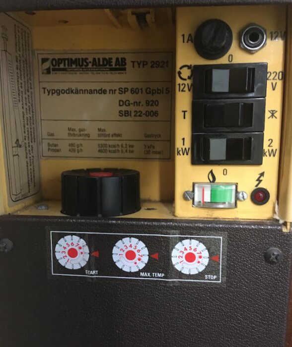 Centralvärmepanna i husvagn med inställningsknappar, manometer och etikett märkt Optimus-Alde AB Typ 2921.