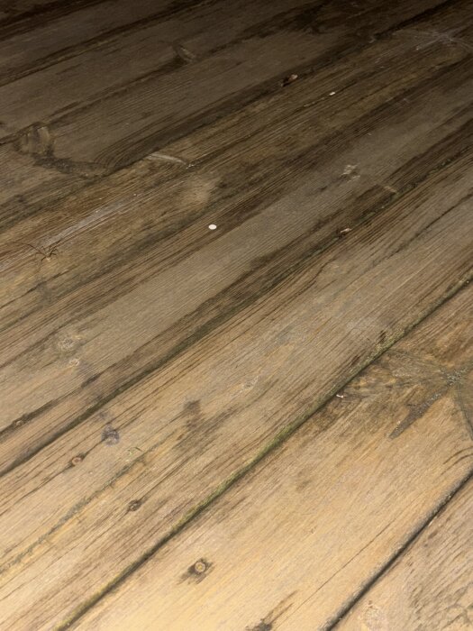 Sliten trätrall med mörka skuggor efter fläckvis betsning, ca fem år efter behandling.