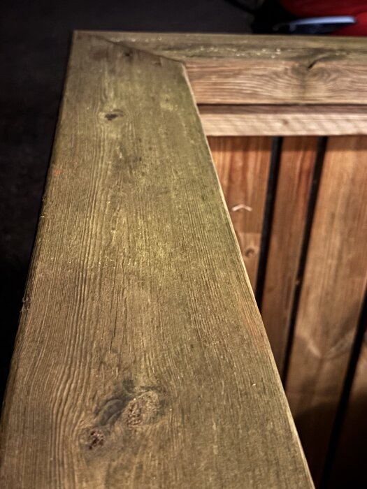 Närbild av ett väderbitet trästaket med synliga ådror och kvistar, fem år efter första behandling med bets.