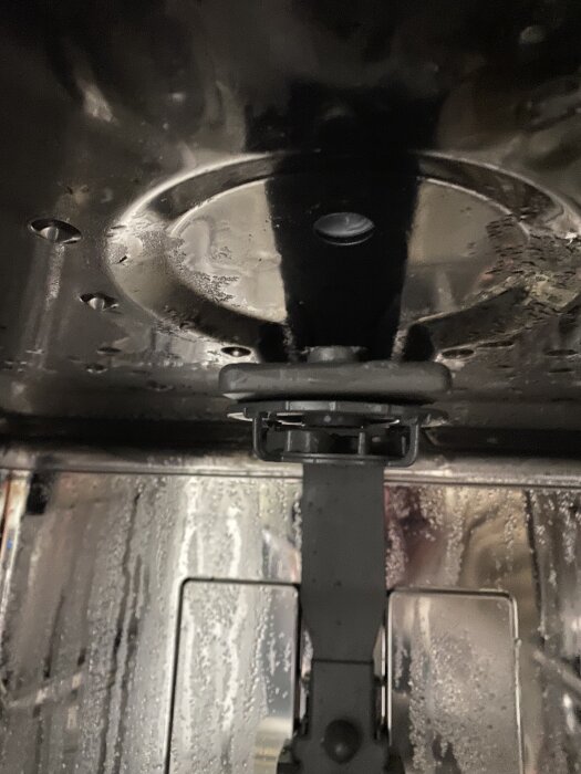 Vattenspridaren i en diskmaskin har lossnat från innertaket, vilket orsakar problem med bestickslådan.