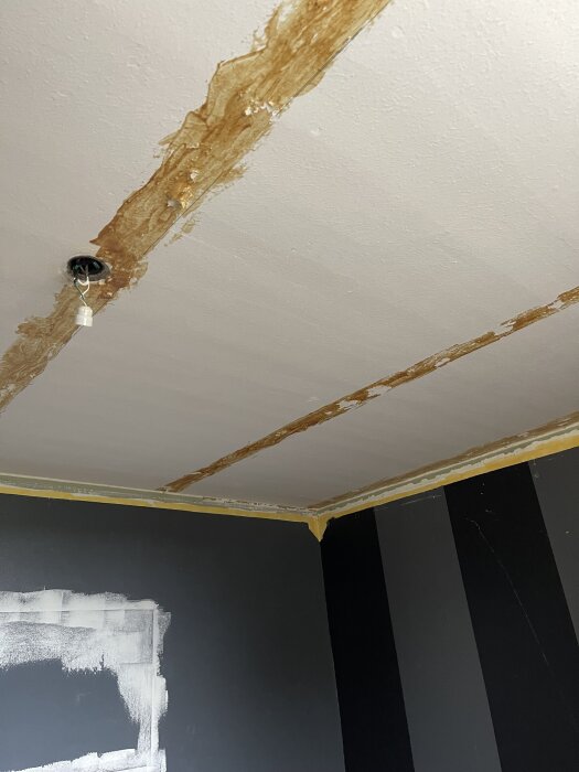 Gästrumstak med kvarvarande limrester från tidigare innertak. Ränder av brunt lim syns mot det vita taket. Frågeställning om färg kan appliceras direkt.