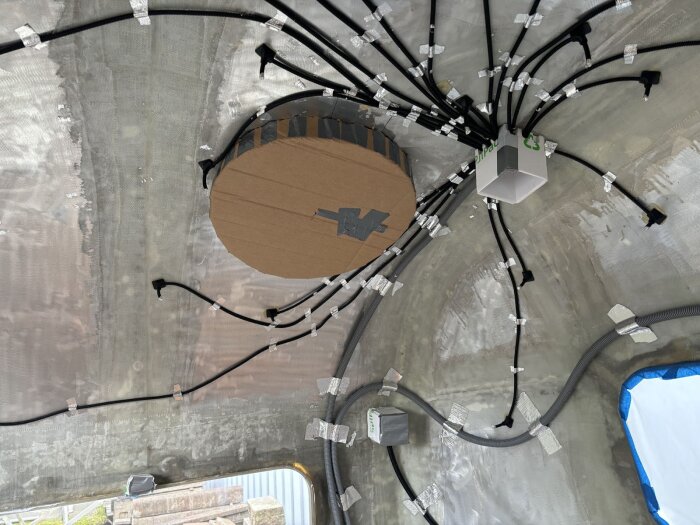 Eldosor och kablage monterade på ett bestruket tak, med wellpapp som skydd inför sprayfoaminsatsen.