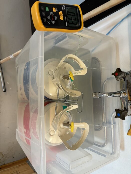 Plastlåda med Froth Pak-kit i vattenbad, termometer visar 23 grader.