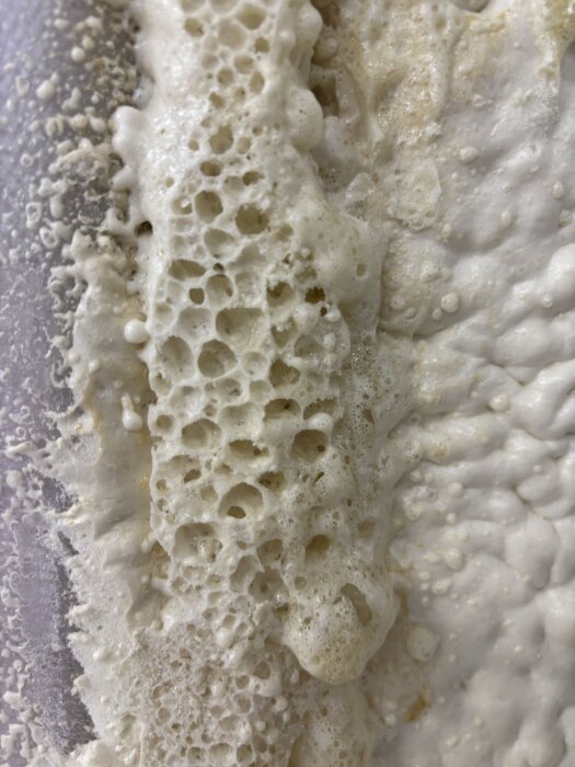 Nära närbild av sprayfoamskum med varierande bubbelstorlekar och ojämn yta.