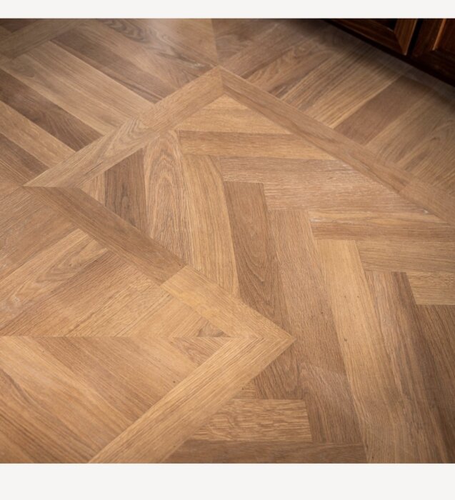 Fiskbensmönstrad parkett med naturlig träfinish, visas från sidan i ett rum.